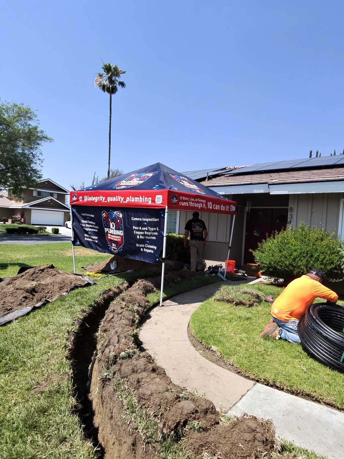 IQ Plumbing branded canopy set up at a repipe job site