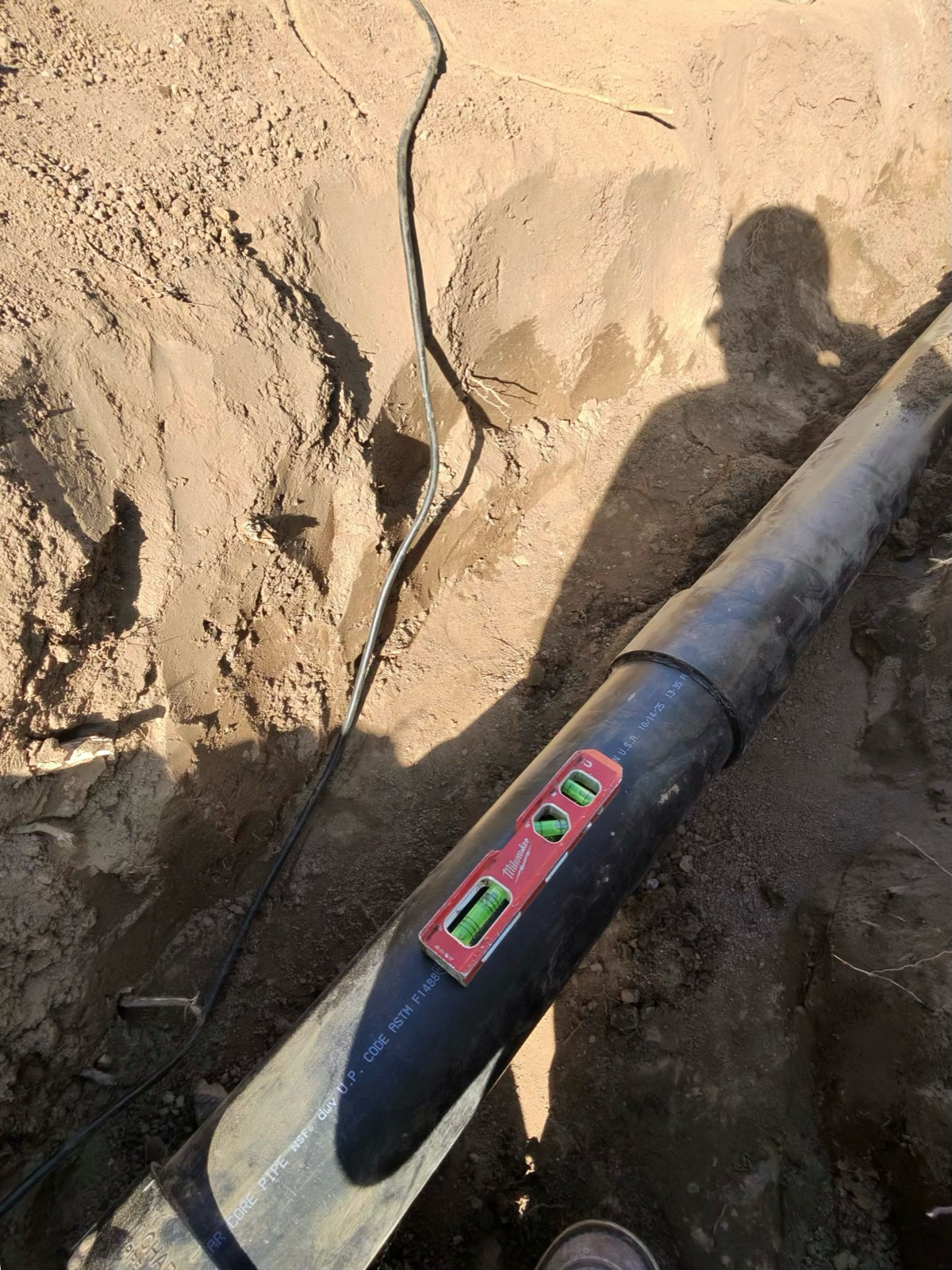 Technician leveling a pipe in a trench